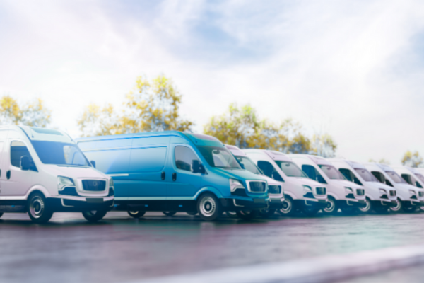 "Linha de vans brancas de transporte de carga estacionadas, representando uma frota de veículos comerciais segurada pela Atenuar Seguros."