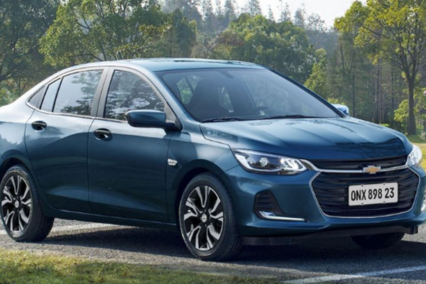 "Chevrolet Onix Plus azul, carro de aplicativo Uber, estacionado em ambiente externo com árvores ao fundo, simbolizando o seguro para motoristas de aplicativo da Atenuar Seguros."